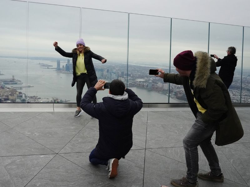 Touristen machen Fotos in riesiger Höhe auf der Plattform The Edge